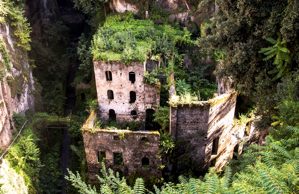 Vue en plongée d'un vieux moulin italien en pierre recouvert par la végétation
