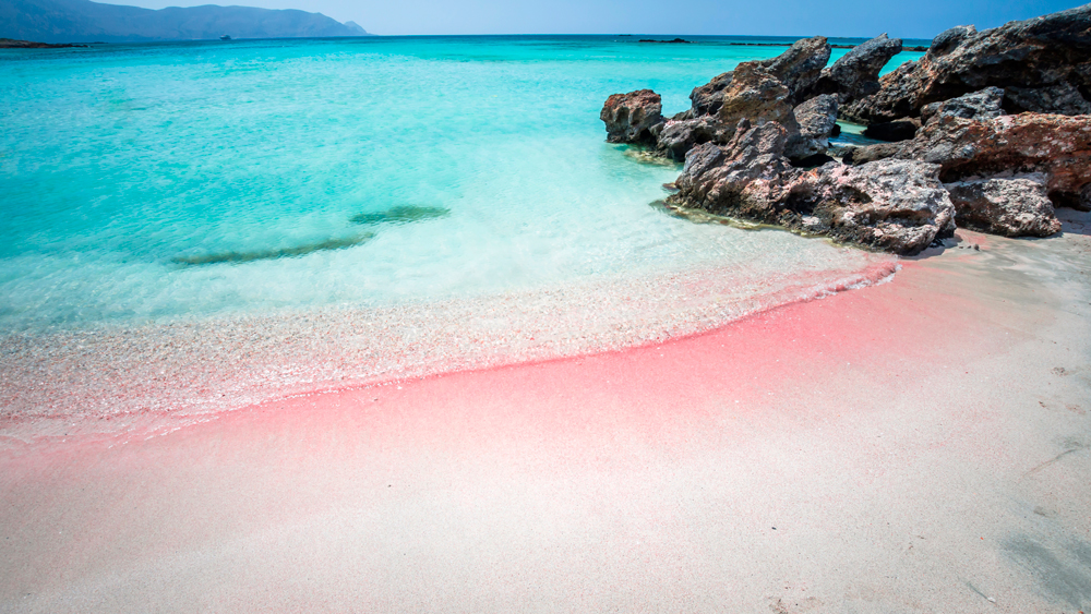 Plage d'Elafonissi: sable rose en premier plan, rochers sur la droite et eau turquoise